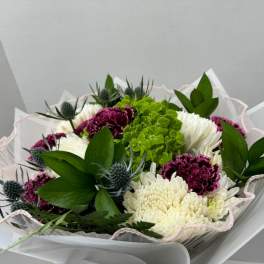 Bouquet of white and magenta flowers with green accents in pink-edged wrap