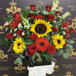 Mixed bouquet of red roses and sunflowers in a black box on a pedestal