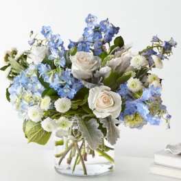 Blue and white bouquet of roses and mixed blooms in a glass vase
