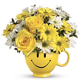 Yellow roses and daisies in a smiley-face mug
