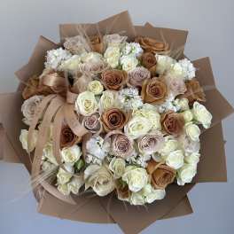 Bouquet of cream, blush, and caramel roses wrapped in brown paper