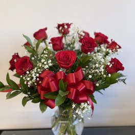 Red roses in a clear glass vase with a red ribbon bow