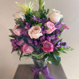 Bouquet of pink and purple flowers in a glass vase with a ribbon