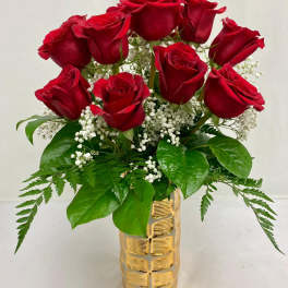 Red roses arranged in a gold vase with baby's breath