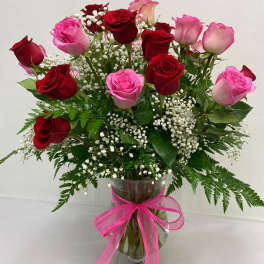 Bouquet of red and pink roses in a glass vase with a pink ribbon