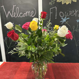 Mixed roses in a clear glass vase with greenery