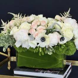 White and blush floral arrangement in a green glass vase