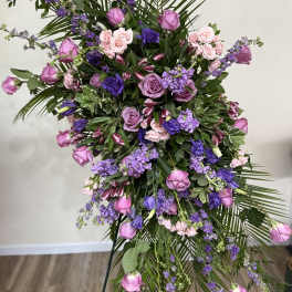 Tall floral spray with pink and purple roses and mixed blooms on a stand