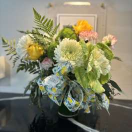 Bouquet of mixed flowers in a green vase with a patterned ribbon