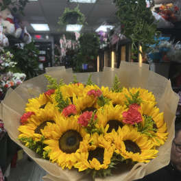 Bouquet of yellow sunflowers with pink carnations wrapped in brown paper