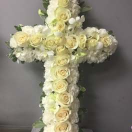 White floral cross with cream roses and white blooms