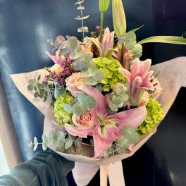 Bouquet of pink lilies, roses, and green hydrangeas wrapped in paper
