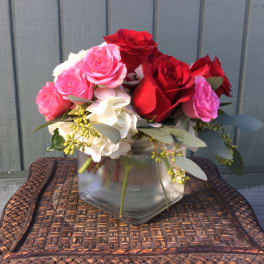 Pink and red roses arranged in a clear glass vase