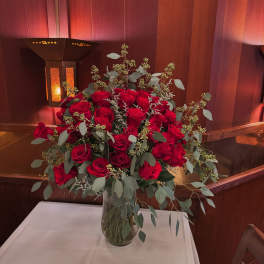 Red rose arrangement in a clear glass vase on a table