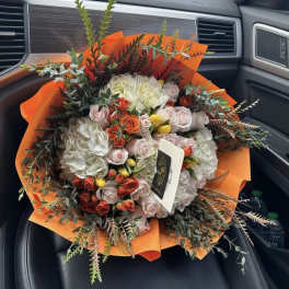 Mixed bouquet of roses and hydrangeas wrapped in bright orange paper