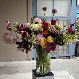 Mixed bouquet of tulips, roses, and calla lilies in a glass vase