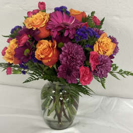 Mixed bouquet of purple, pink, and orange flowers in a glass vase