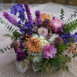 Colorful bouquet with purple, pink, and orange flowers on white tulle