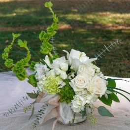 White floral arrangement with roses and lilies in a glass vase