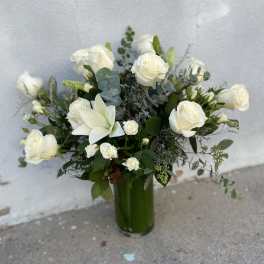 White roses and lilies arranged in a tall green vase
