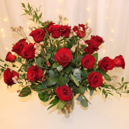 Red roses arranged in a clear glass vase with greenery