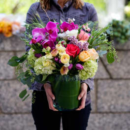 Mixed bouquet of orchids, roses, and hydrangeas in a glass vase