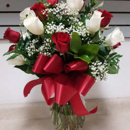Red and white roses in a glass vase with a red ribbon