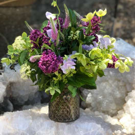 Mixed bouquet in a textured glass vase with purple, lavender, and yellow blooms