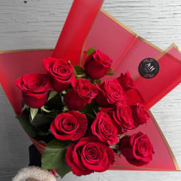 Bouquet of red roses wrapped in red paper with gold trim
