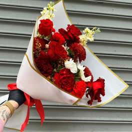 Bouquet of red roses and red carnations wrapped in white paper