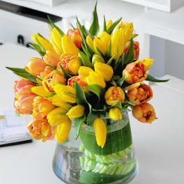 Yellow and orange tulips arranged in a clear glass vase