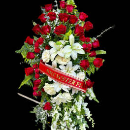 Standing floral spray of red roses and white lilies with a red ribbon