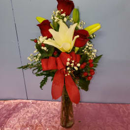Bouquet of red roses and white lilies in a glass vase with a red ribbon