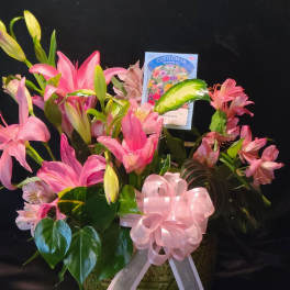 Pink lilies and alstroemeria in a basket with a pink ribbon bow