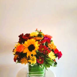 Colorful mixed flower arrangement in a square glass vase