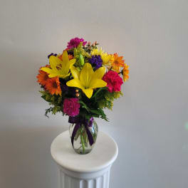 Colorful bouquet of lilies, daisies, and carnations in a glass vase
