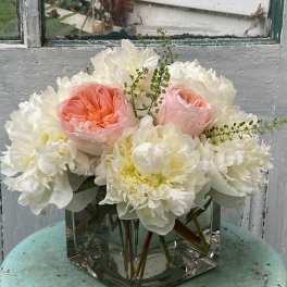 Pink and white flowers arranged in a square glass vase