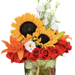 Bouquet of red roses, sunflowers, orange lilies, and white lisianthus in a glass vase