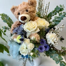 Teddy bear in a bouquet with white roses and purple flowers