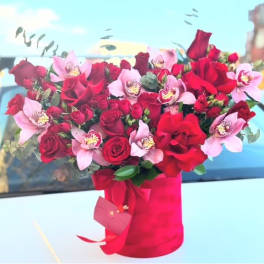 Red roses and pink orchids in a red wrapped bouquet