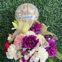 Birthday balloon above a mixed bouquet in a glass vase