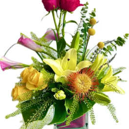 Mixed bouquet in a clear glass vase with lilies, roses, and pink blooms