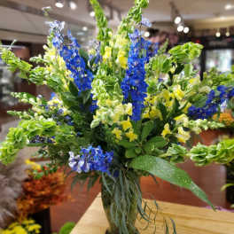Tall bouquet of blue and yellow flowers in a glass vase