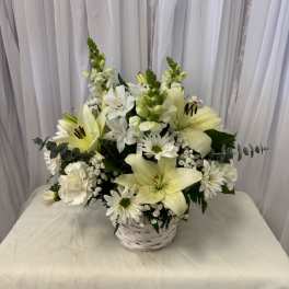 White lilies and daisies arranged in a white basket
