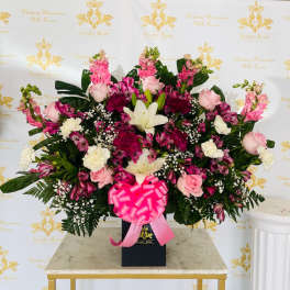 Large pink and white floral arrangement in a black box with a ribbon bow