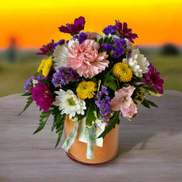 Mixed bouquet of pink, white, yellow, and purple flowers in a glass vase