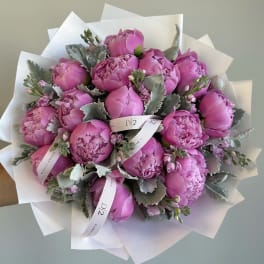 Pink peony bouquet wrapped in white paper with a ribbon