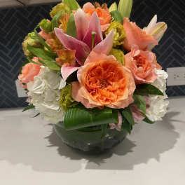 Bouquet of orange and pink flowers in a glass bowl vase