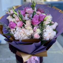 Bouquet of pink and white roses with pale hydrangeas wrapped in purple paper