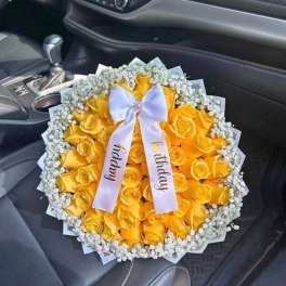 Yellow rose bouquet with a white ribbon in a car seat